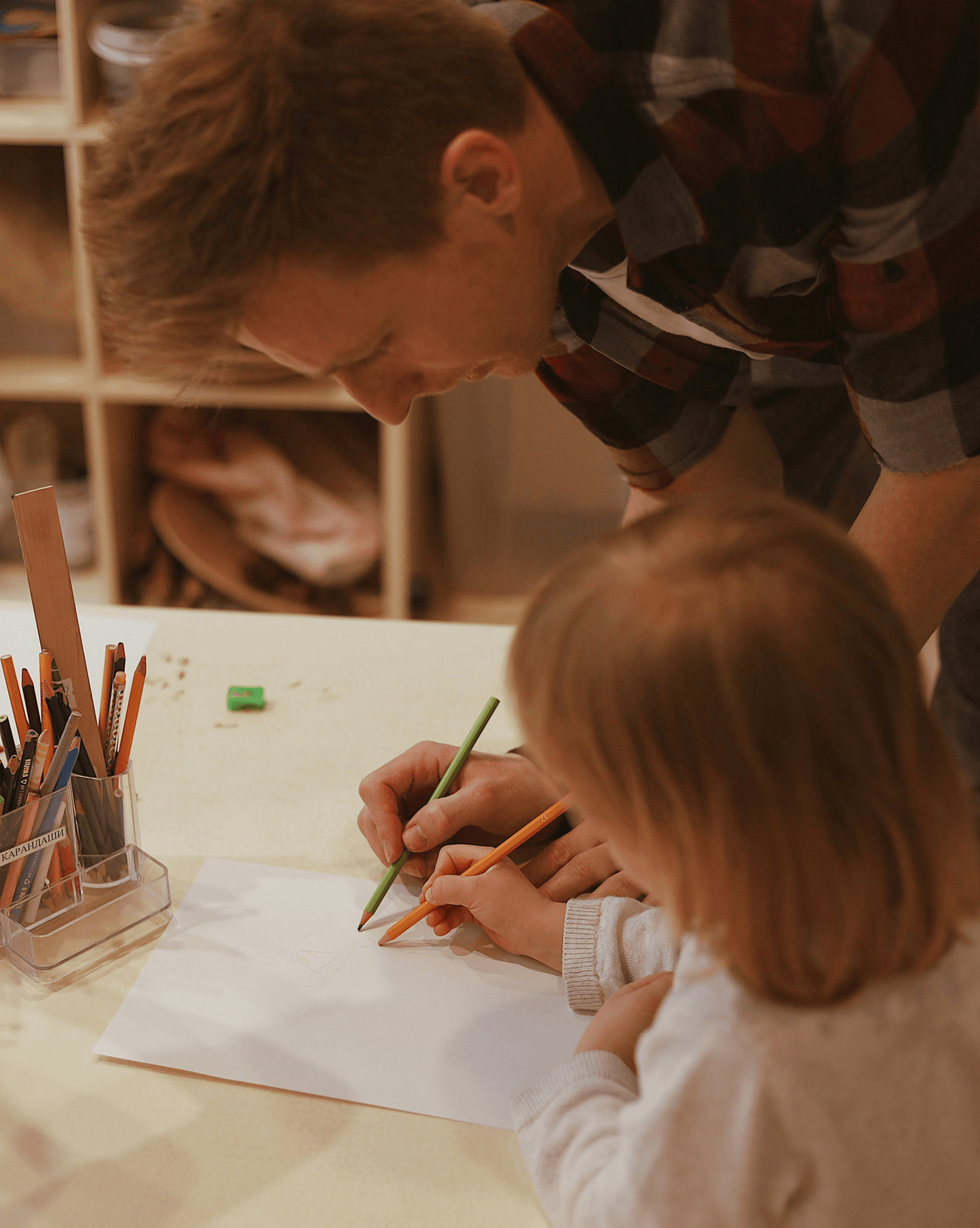 An adult helping a child draw